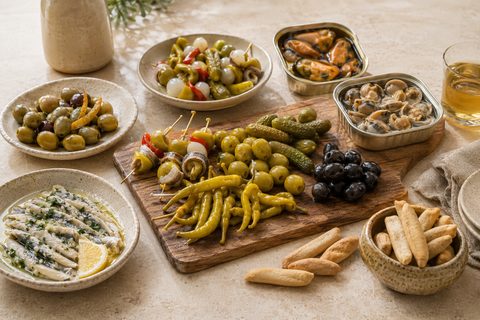 Mesa de aperitivo con boquerones, conservas, aceitunas y encurtidos